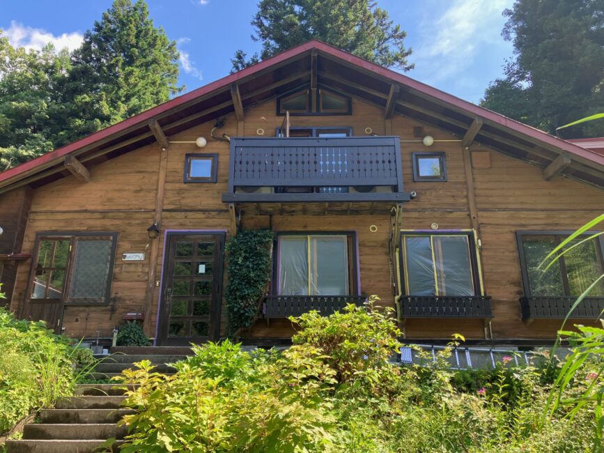 an A frame wooden loge with balconies, flower boxes and a garden